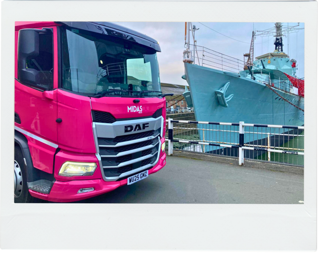 A bright pink Midas Waste dustcart parked in front of a ship docked at The Historic Dockyard Chatham in Medway