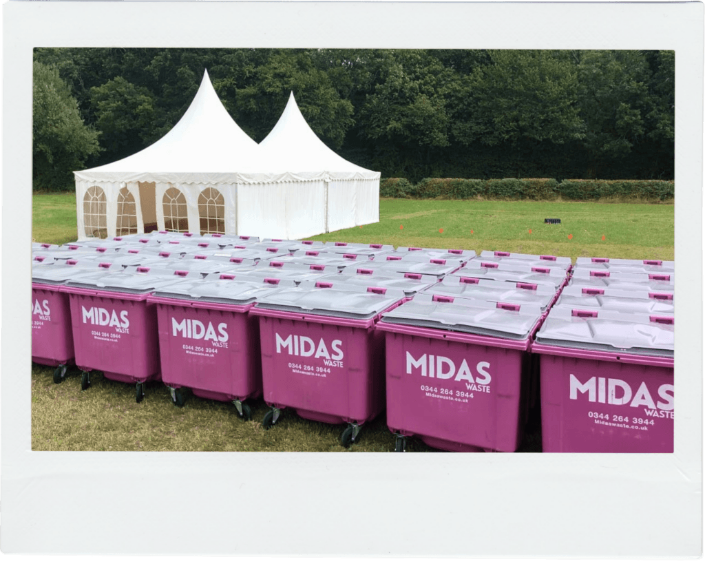A large quantity of Midas Waste wheelie bins in a wide open field with a marquee in the background